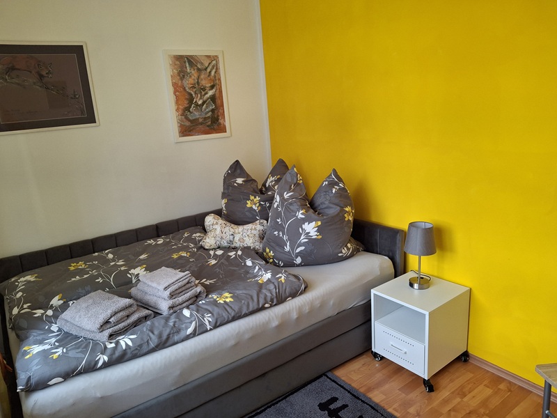 gelbes Schlafzimmer mit Kleiderschrank und Schreibtisch in der Unterkunft Chorin Kloster